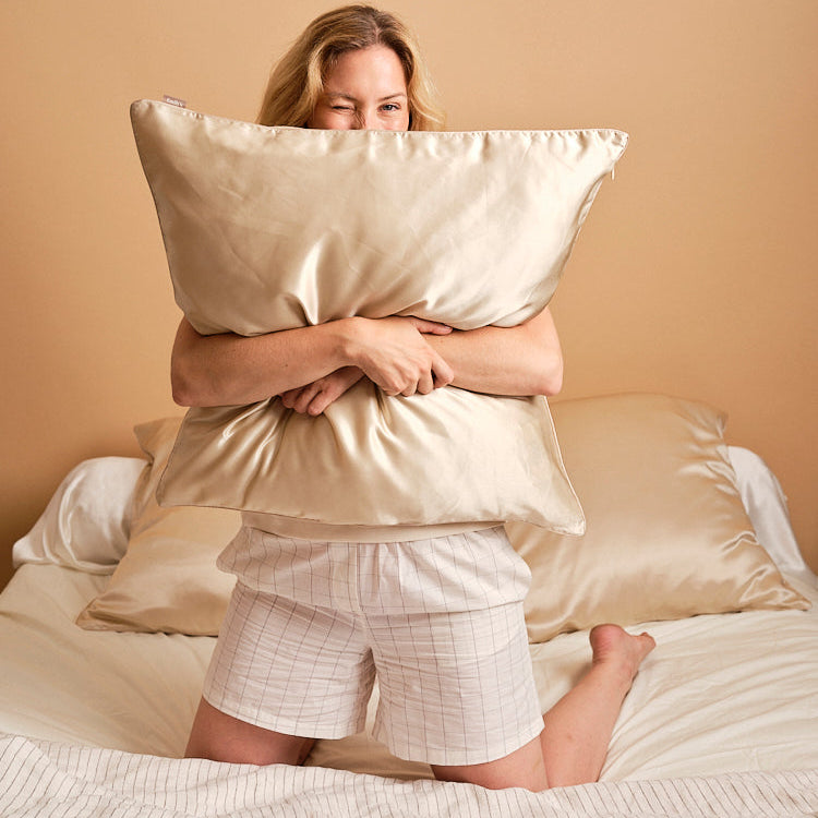 Woman hugging a pillow in a champagne mulberry silk pillowcase